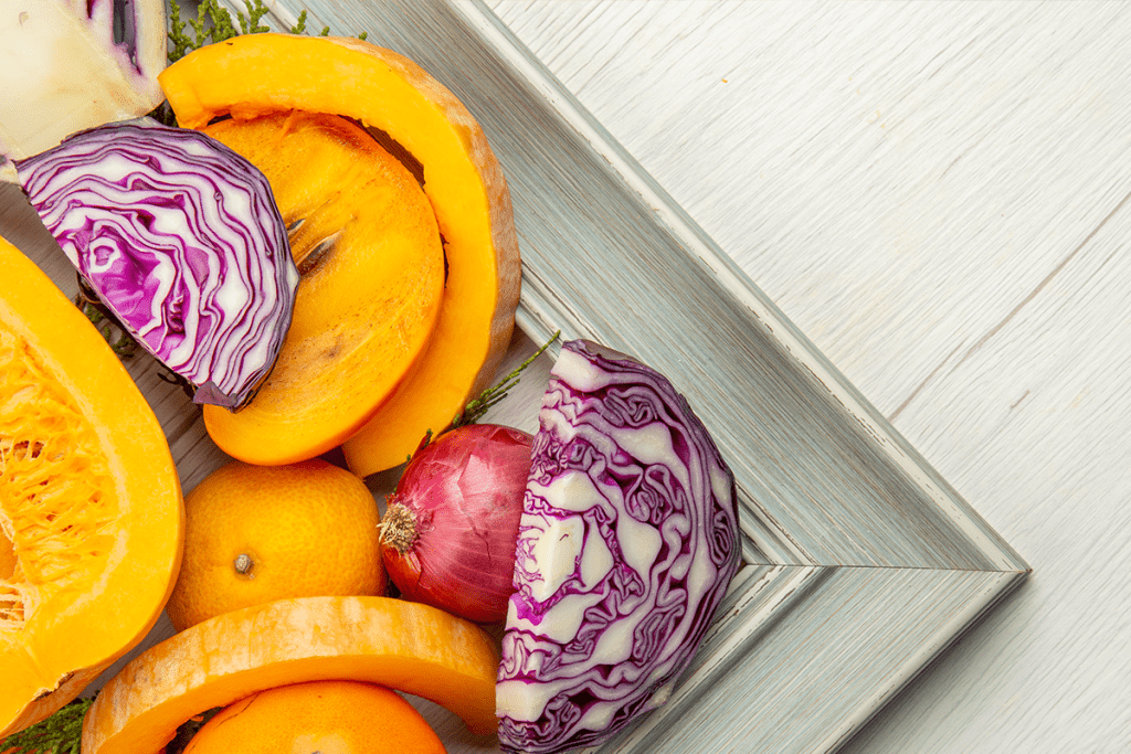 Frutas y verduras de otoño frescas sobre una mesa con tonos cálidos